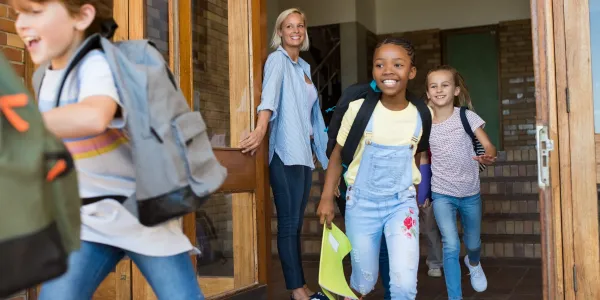 Elementary school children running out of school smiling