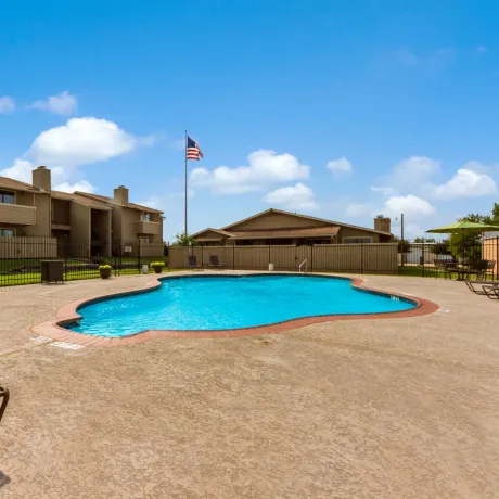 Living Oaks Apartments in Red Oak, TX with gated sparkling community pool and sun deck surrounded by green grass