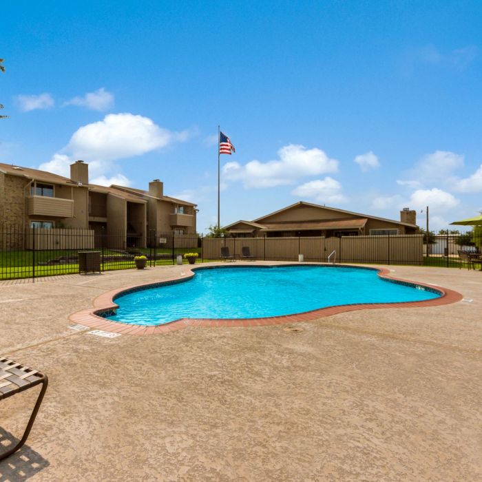 Living Oaks Apartments in Red Oak, TX with gated sparkling community pool and sun deck surrounded by green grass