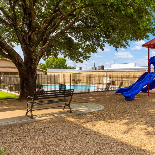 Living Oaks Apartments in Red Oak, TX with community playground, mature tree, and park bench